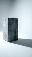 Weathered concrete block casting dramatic shadow on white surface in minimalist studio setting for architectural and construction design projects.