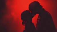 Romantic couple silhouettes touching foreheads in intimate moment against dramatic red lighting for Valentine's Day and love concepts.