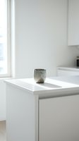 Minimalist ceramic vessel with textured glaze sitting on white kitchen counter near window, showcasing modern home decor and interior design styling.
