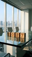 Wooden blocks spelling 2027 on a glass conference table in a modern office with city skyline view, symbolizing business planning and goals.