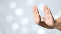 Open hands reaching upward in prayer or meditation gesture against soft bokeh light background for spiritual wellness concepts.