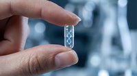 Hand holding transparent glass slide with DNA double helix structure for genetic research and biotechnology applications in modern laboratory setting.