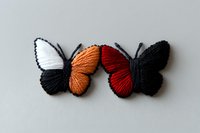Handcrafted embroidered butterfly brooches featuring white, orange, and red wings with black details on light background, suitable for fashion and craft projects.