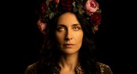 Middle Eastern woman with floral crown of roses in dark moody portrait photography. Professional headshot with dramatic lighting on black background.