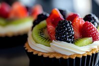 Fresh fruit tart with kiwi strawberry blackberry and cream on pastry base. Gourmet dessert bakery confection for cafe menu restaurant display.