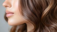 Young woman with glossy brown wavy hair and natural makeup showcasing healthy hair care and beauty routine for salon and cosmetic advertising.