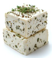 Fresh feta cheese blocks with herbs and spices stacked on white background, garnished with rosemary sprigs. Mediterranean dairy product isolated for food design.