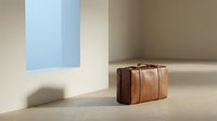 Vintage brown leather suitcase in minimalist interior with natural sunlight and shadows creating elegant travel concept for modern design.