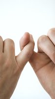 Two hands making a pinky promise gesture on a white background, symbolizing trust, commitment, and friendship between people.