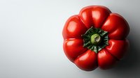 Fresh ripe red bell pepper with distinctive ribbed shape and green stem viewed from above on light background, dramatic side lighting creates depth and shadow.