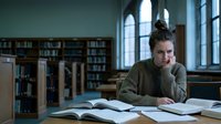 Young woman student studying in university library with open books, concentrated learning and academic research in quiet reading room with bookshelves.