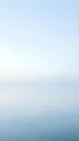 Serene seascape with calm waters and soft horizon line, featuring tranquil ocean meeting pale sky in minimalist composition for wellness and travel designs.