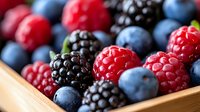 Fresh organic berries mix of raspberries, blackberries and blueberries in wooden box, macro food photography with selective focus for healthy eating.