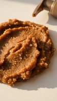 Creamy peanut butter spread with cinnamon sugar topping and wooden spoon on white surface, ready for cooking and baking projects.