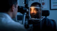 African American man receiving comprehensive eye examination from optometrist using advanced diagnostic equipment in modern clinic for vision care.