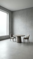 Minimalist dining room interior with concrete walls, polished cement floor, round taupe table, two modern chairs, and large window providing natural light for contemporary home design projects.