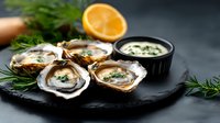 Fresh oysters served on black stone plate with herbs, lemon and sauce. Raw seafood appetizer with garnish on dark background. Gourmet restaurant dish.