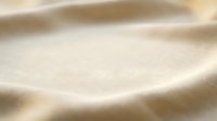 Smooth beige sand dunes with soft flowing curves and gentle shadows creating natural abstract landscape texture for backgrounds and design projects.