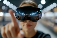 Young Asian woman wearing virtual reality headset with reflection of digital environment, pointing finger in futuristic space. Modern VR technology concept.