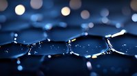 Macro photography of water drops with bokeh lights creating abstract pattern in dark blue tones. Reflective surface shows distorted light circles.