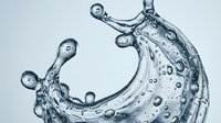 Dynamic water splash with droplets and bubbles creating curved motion against clean background for refreshing beverage and hydration concepts.
