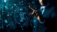 Professional in business suit interacts with glowing digital lightbulb hologram against dark background with futuristic interface and blue technology elements.