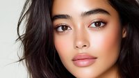 Young Asian woman with natural makeup, glowing skin, and dark flowing hair against light background, showcasing modern beauty and cosmetic trends.