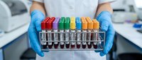 Laboratory technician in blue gloves holding rack of colorful blood test tubes for medical analysis and diagnostic testing in clinical setting.