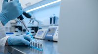 Laboratory technician in blue gloves using pipette for precise sample analysis in modern research facility with scientific equipment and test tubes.