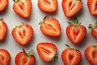 Fresh strawberry halves arranged in rows showing juicy red flesh and natural pattern on neutral background.