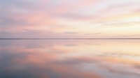 Serene sunset landscape with soft pink and golden hues reflecting across calm water, creating a tranquil atmosphere suitable for wellness, meditation, and relaxation design projects.