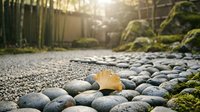 Golden autumn leaf resting on smooth river stones in peaceful zen garden with warm sunlight filtering through bamboo fence creating tranquil meditation space.