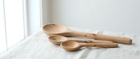 Wooden kitchen utensils set with spoons and ladles on white marble surface near window for cooking and food preparation in modern home interior.