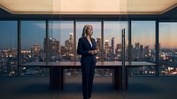 Professional businesswoman in navy suit standing confidently in modern office with panoramic city skyline view at sunset for corporate leadership concepts.