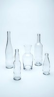 Empty clear glass bottles and drinking glass arranged on white background for minimalist design projects and eco-friendly packaging concepts.