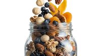 Assorted nuts, dried fruits, and berries overflowing from glass jar on white background. Healthy snack mix for nutrition, wellness, and dietary content.