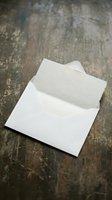 White envelope with textured paper card on rustic wooden surface for wedding invitations and correspondence mockup design projects.