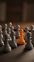 Orange pawn stands out among white pawns on wooden surface, symbolizing uniqueness, leadership, and standing out from crowd for business concepts.