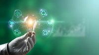 Business hand holding glowing light bulb with green energy icons representing sustainable innovation and eco-friendly technology solutions for environmental progress.