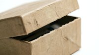 Opened brown cardboard shipping box with lid partially lifted revealing dark interior space for packaging and delivery purposes.