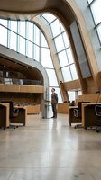 Businessman standing in modern architectural interior with curved wooden elements, arched windows, and polished concrete floors, suitable for corporate and business concepts.