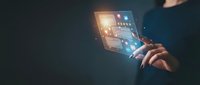 Businessperson holding glowing digital tablet with illuminated interface icons and data visualization, representing technology innovation and digital transformation for business solutions.
