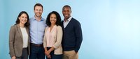 Diverse professional business team of four colleagues standing together smiling in modern office environment for corporate teamwork and collaboration.
