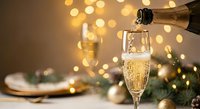 Champagne pouring into elegant flute glass with golden bokeh lights and festive decorations creating luxurious celebration atmosphere for New Year holidays.