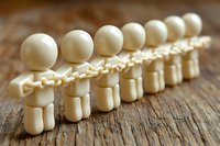 White wooden figures standing in line on rustic wood surface, symbolizing unity, teamwork and organizational structure in business concept.