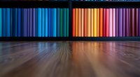 Vibrant rainbow colored books arranged on dark wooden shelf with dramatic lighting and reflective hardwood floor creating colorful gradient effect.