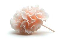 Delicate peach-colored paper flower with ruffled petals isolated on white background, perfect for wedding decorations and craft projects.