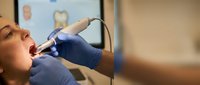 Young woman receiving dental treatment with modern equipment in professional clinic setting for oral health care and preventive dentistry procedures.