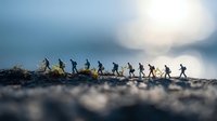 Silhouettes of hikers walking in line along mountain ridge at sunrise, dramatic foggy landscape with bokeh effect in blue tones. Adventure outdoor scene.