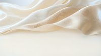 Soft beige fabric with gentle folds and waves creating elegant textile background for luxury fashion, interior design, and sophisticated branding projects.